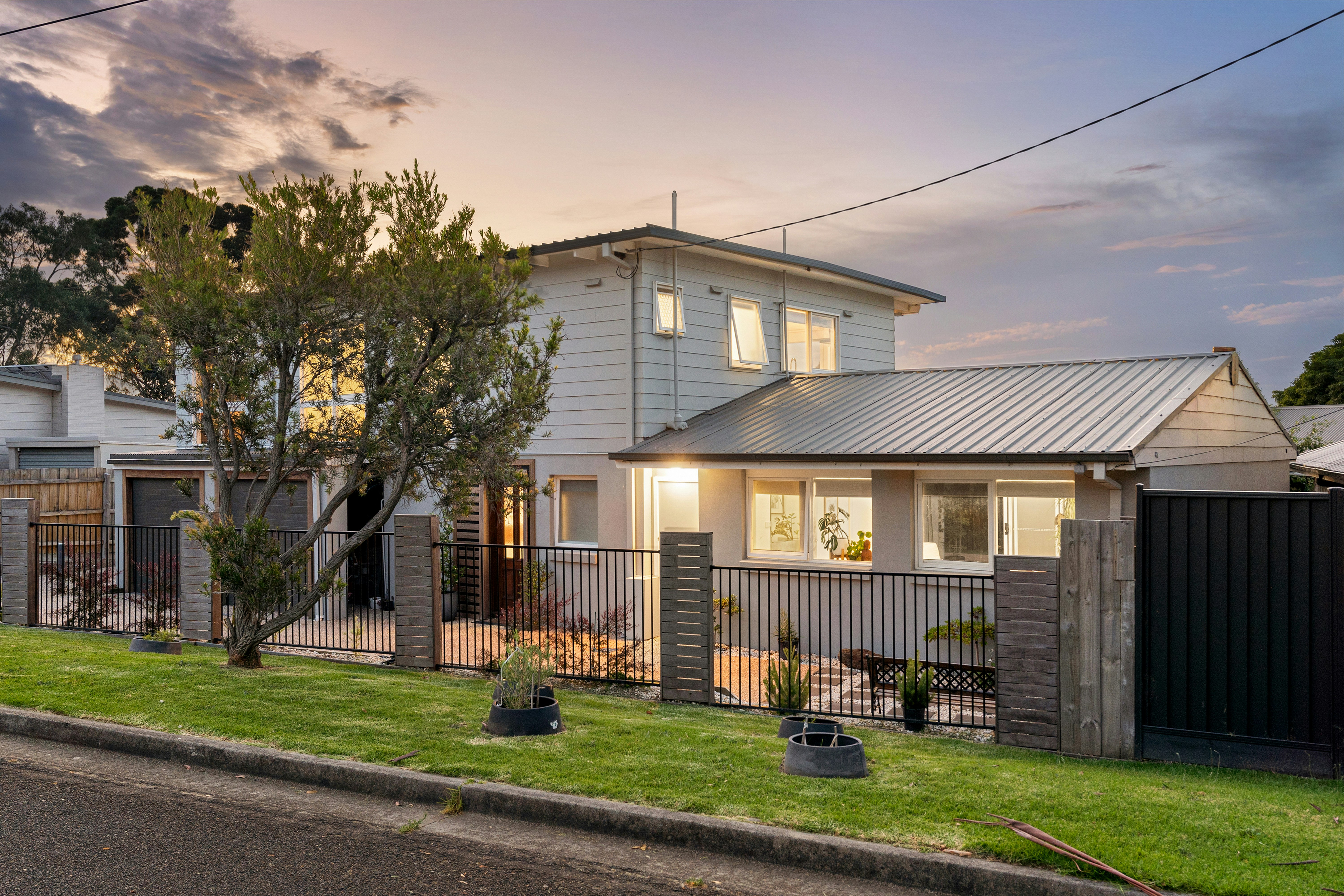 Renovated two-storey home at dusk with lit interior